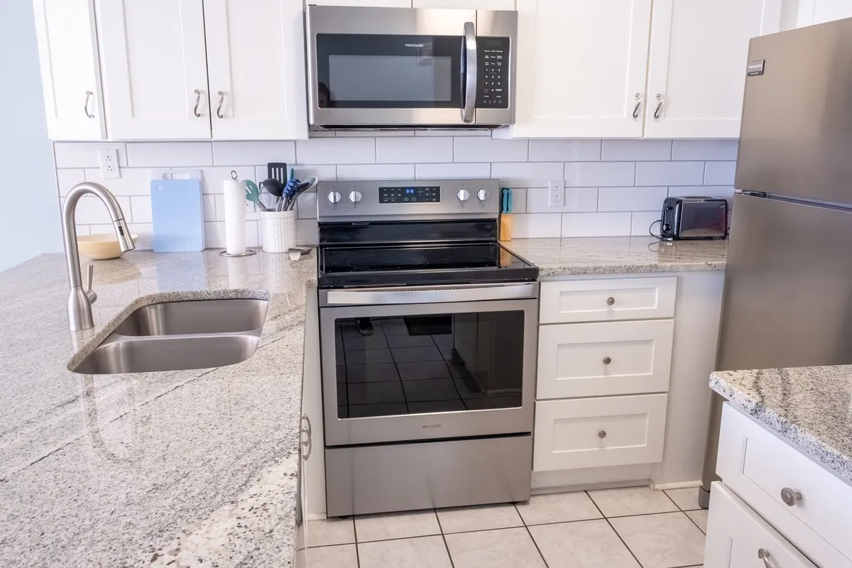 This image showcases a modern kitchen with stainless steel appliances, granite countertops, and bright white cabinetry. The space is open and inviting, with plenty of workspace for meal prep or entertaining. The clean lines and up-to-date finishes emphasize functionality and comfort, making it ideal for both everyday use and festive gatherings.