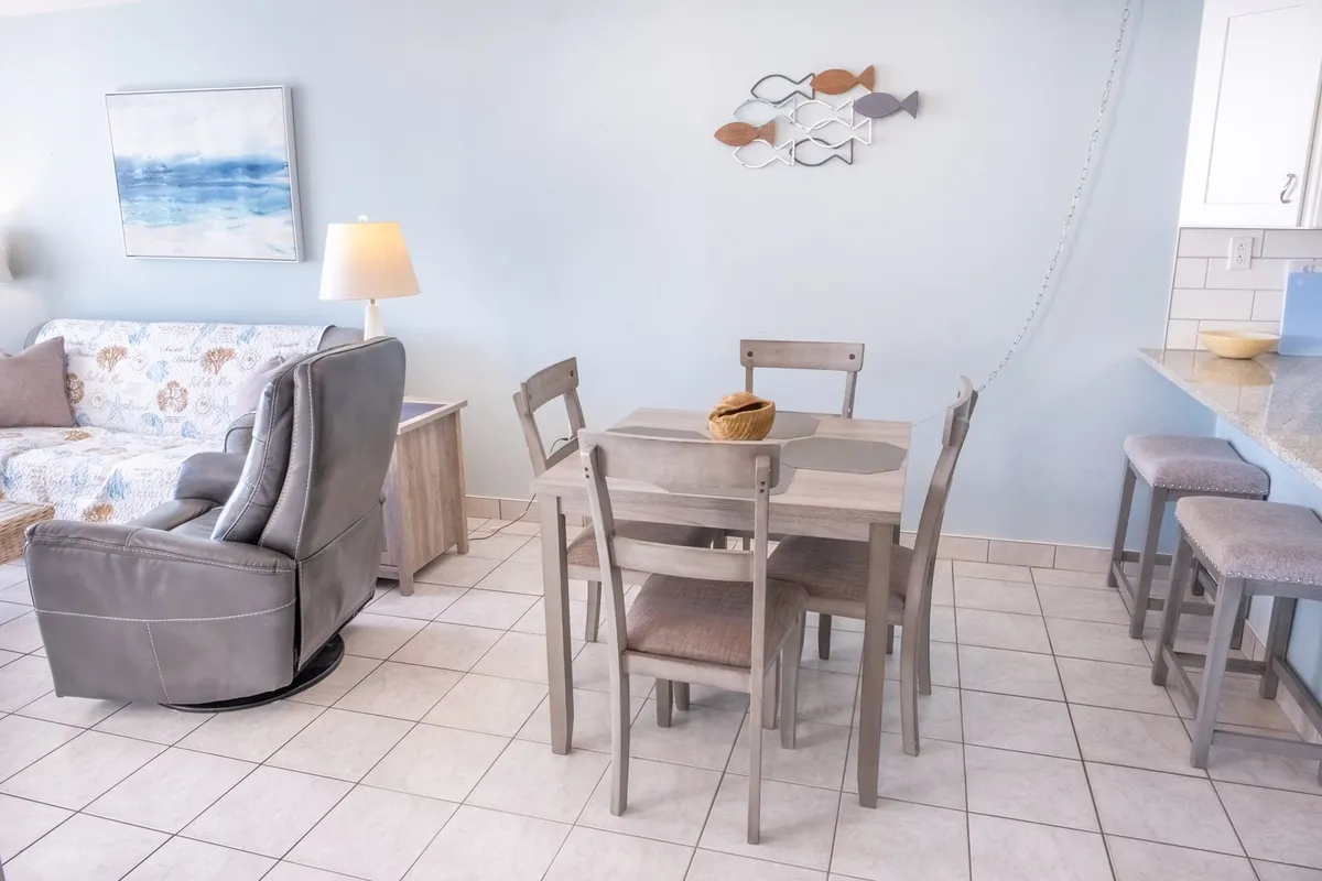 This image centers on the adjacent dining area, featuring a spacious dining table with ample seating. The setting is both comfortable and stylish, designed for shared meals, family conversations, and group planning sessions. Soft lighting and tasteful wall art contribute to an atmosphere of warmth and inclusion.